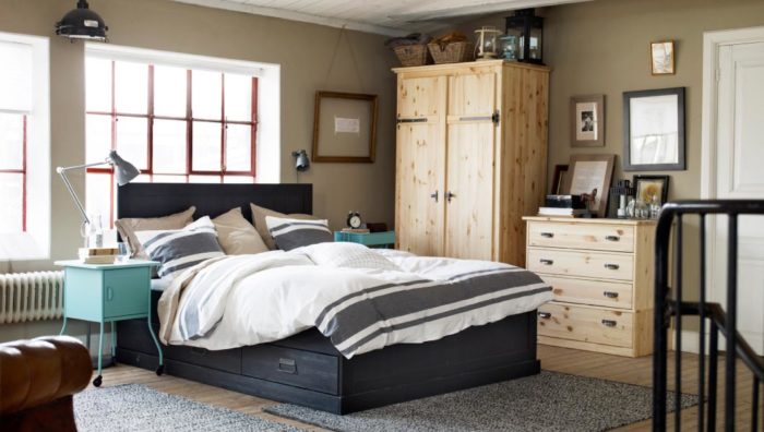 غرفة نوم بسيطة جداً وجميلة وتحتوي عل سرير باللون الاسود ودولاب صغير خشبي