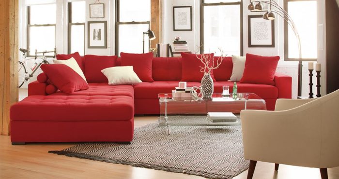 غرفة معيشة أمريكاني تتكون من ركنة حمراء مع وسائد باللون البيج مع ترابيزة زجاجية روعة