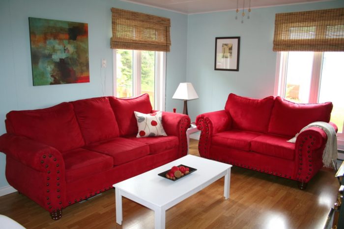 غرفة معيشة حلوة جداً مكونة من 2 كنبة حمراء وترابيزة بيضاء شيك جداً