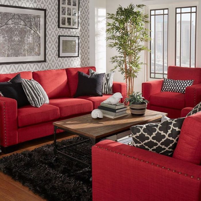 غرفة معيشة مكونة من انترية أحمر سادة ويحتوي على وسادات سوداء منقوشة وترابيزة خشبية